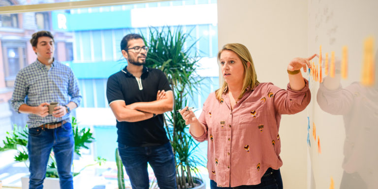 Photo of three people in front of a whiteboard with sticky notes